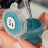 Close-up of acrylic paint being applied to a numbered canvas cell