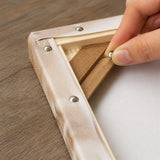 fixing the canvas to the frame back with metal push pins | DIY Wooden Canvas Stretcher Frame